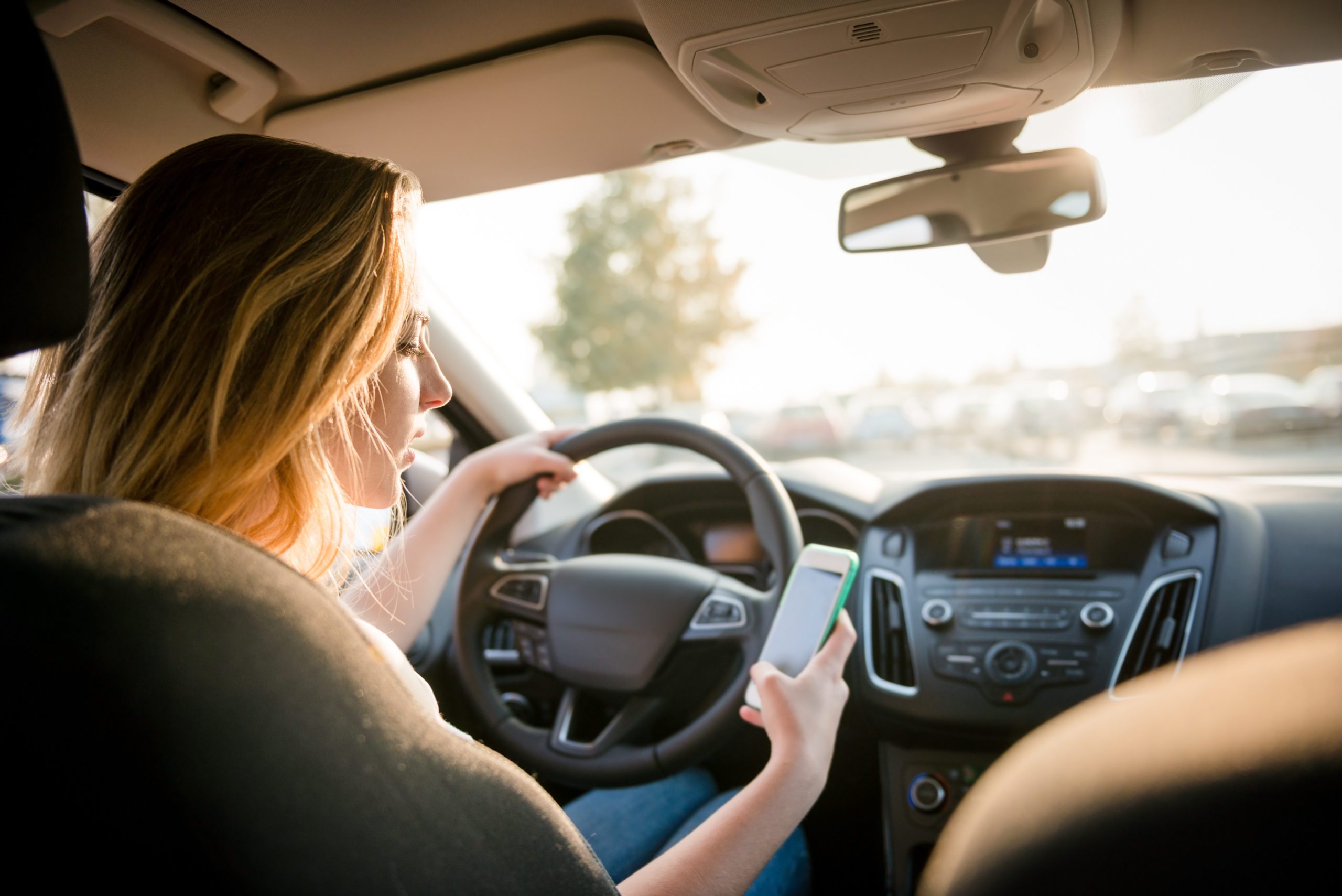 Young,Woman,Looking,To,Her,Smartphone,While,Driving,Car,-